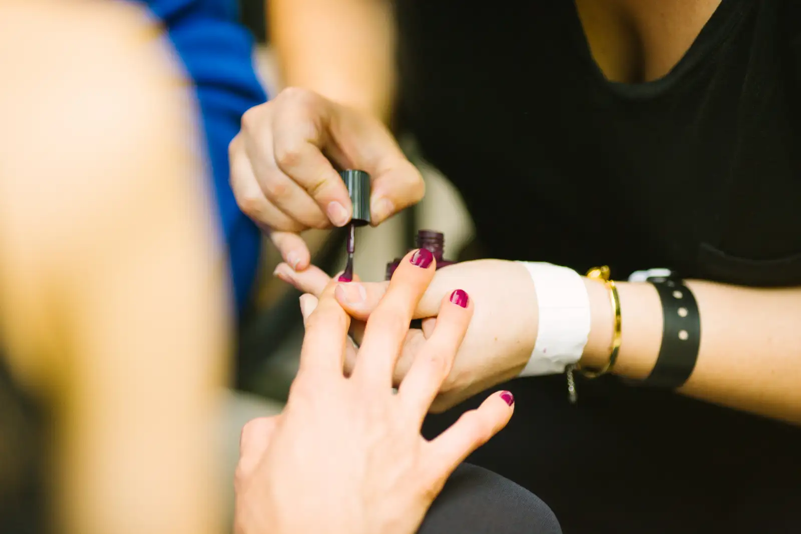 A manicurist’s hands painting polish onto a client’s fingernails